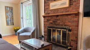 Una sala de estar con chimenea, un sofá, un sillón y un baúl antiguo.