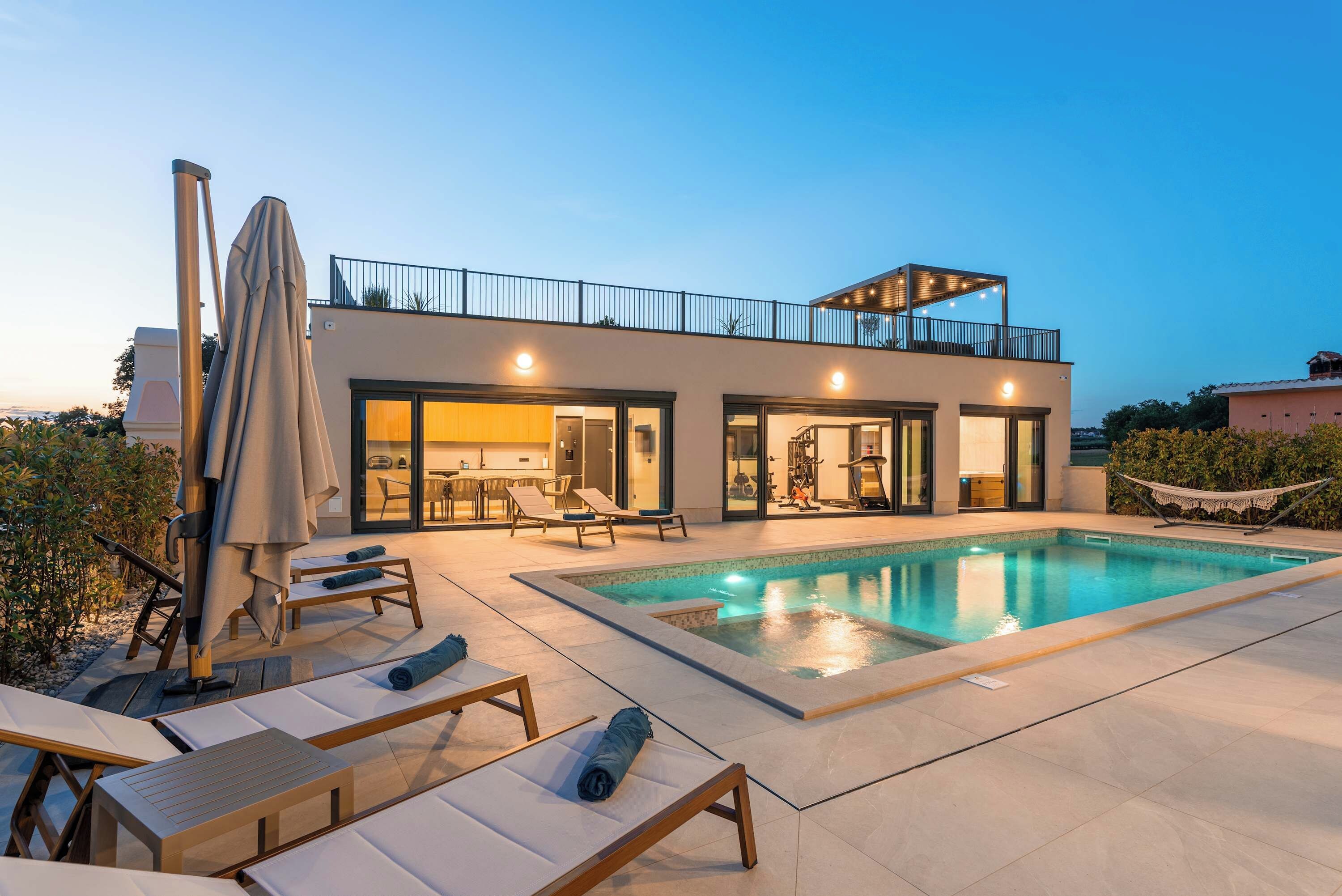 A modern house with a swimming pool, outdoor seating, and a balcony.