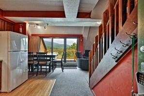 A compact kitchen with a refrigerator, dining table, and chairs. There is a balcony with a view of greenery. - Mountain Green Condo 3f11 2 Bedroom Condo (Killington)