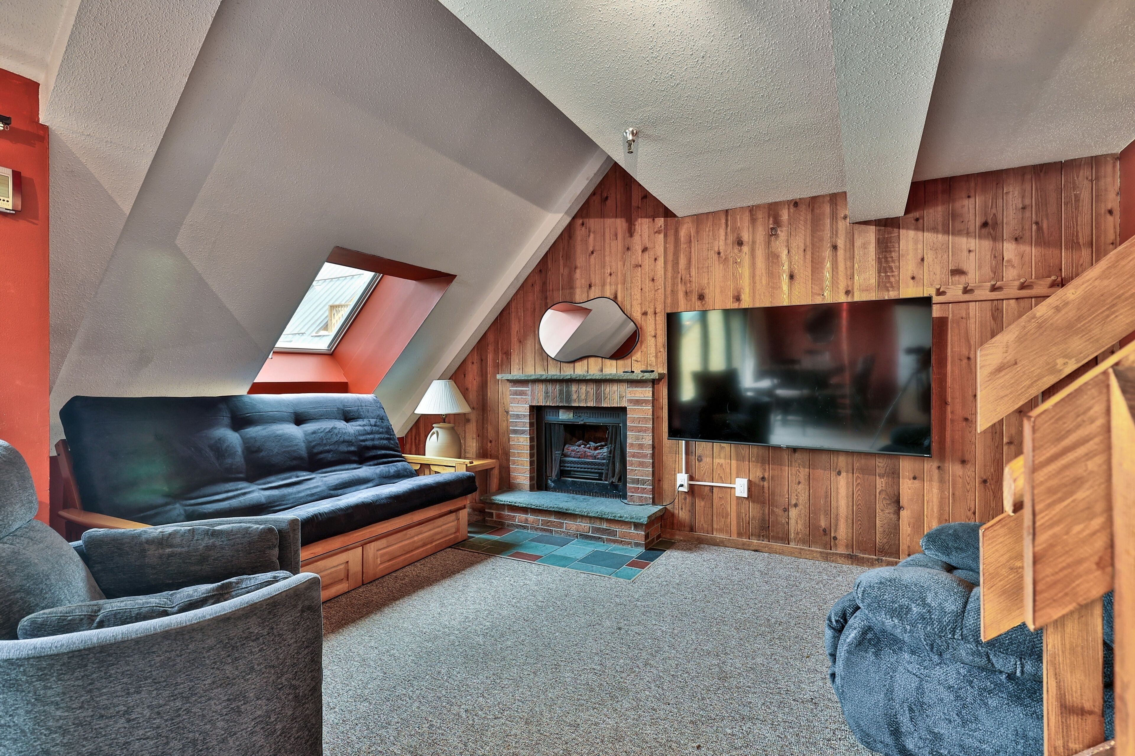 A loft-style living room with a fireplace, a sofa, a TV, and a wooden ceiling.
