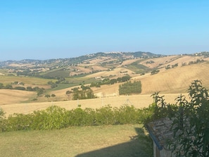 Paisatge rural amb turons suaus, cases disperses i un cel serè.