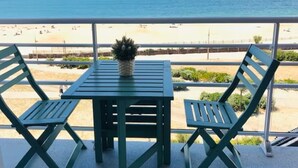 Varanda com mesa e duas cadeiras, vista para a praia.