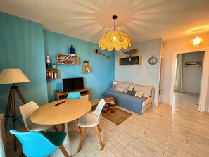 A living room with a round table, chairs, a sofa, a television, and a decorative hanging light fixture. - Exceptional Ocean View in Hossegor. (Soorts-Hossegor)