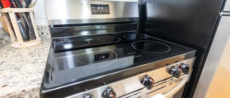 Une cuisinière en acier inoxydable, dotée de quatre brûleurs et d’un écran numérique, située dans une cuisine avec un comptoir en granit.