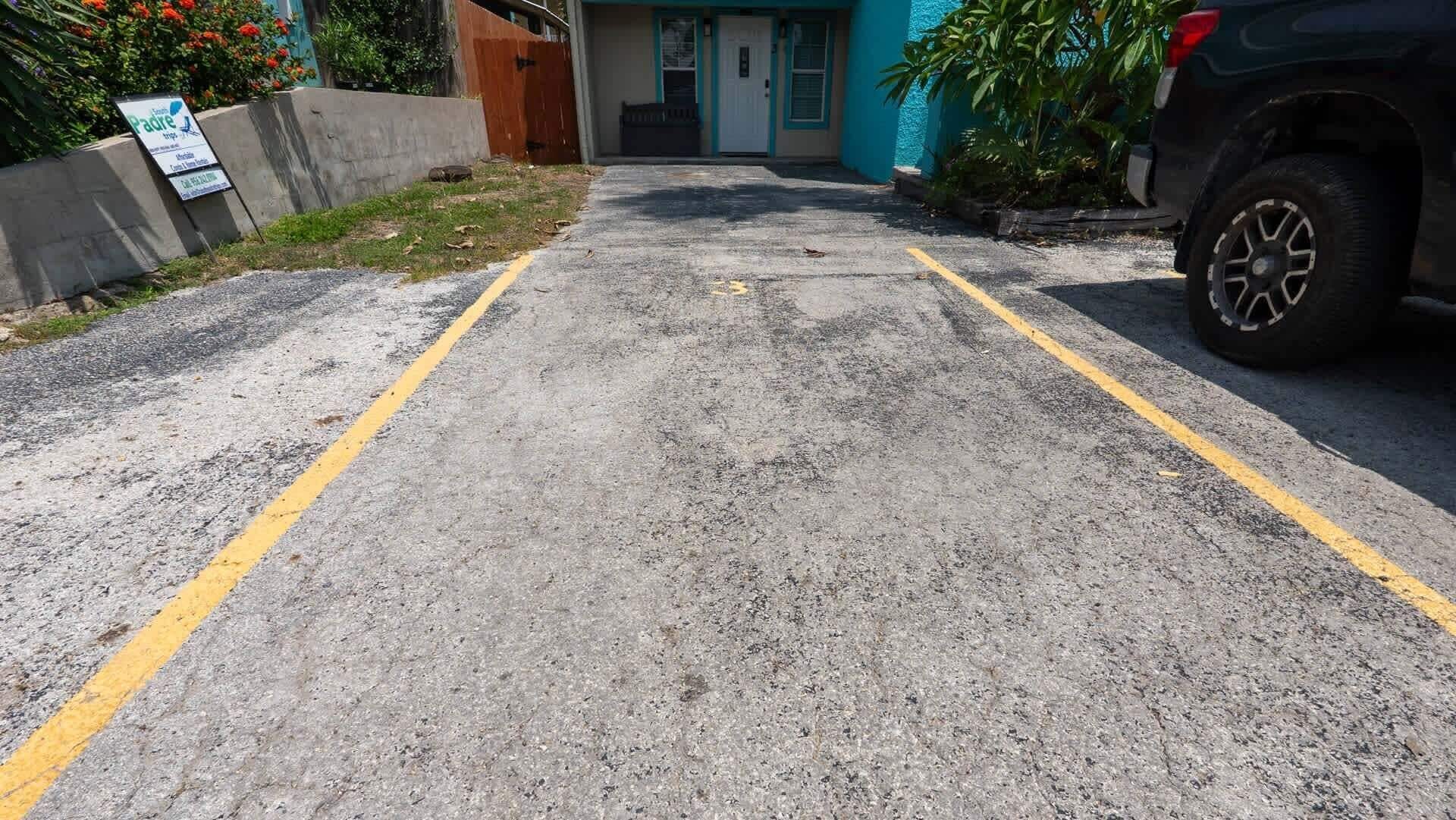 A parking area with a concrete surface and yellow lines.