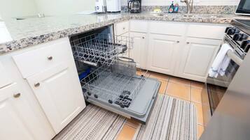 A kitchen with white cabinets, a dishwasher, a stove, and a granite countertop.
