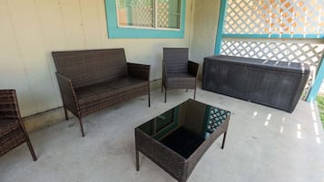A patio area with wicker furniture, including a sofa, chairs, and a coffee table.