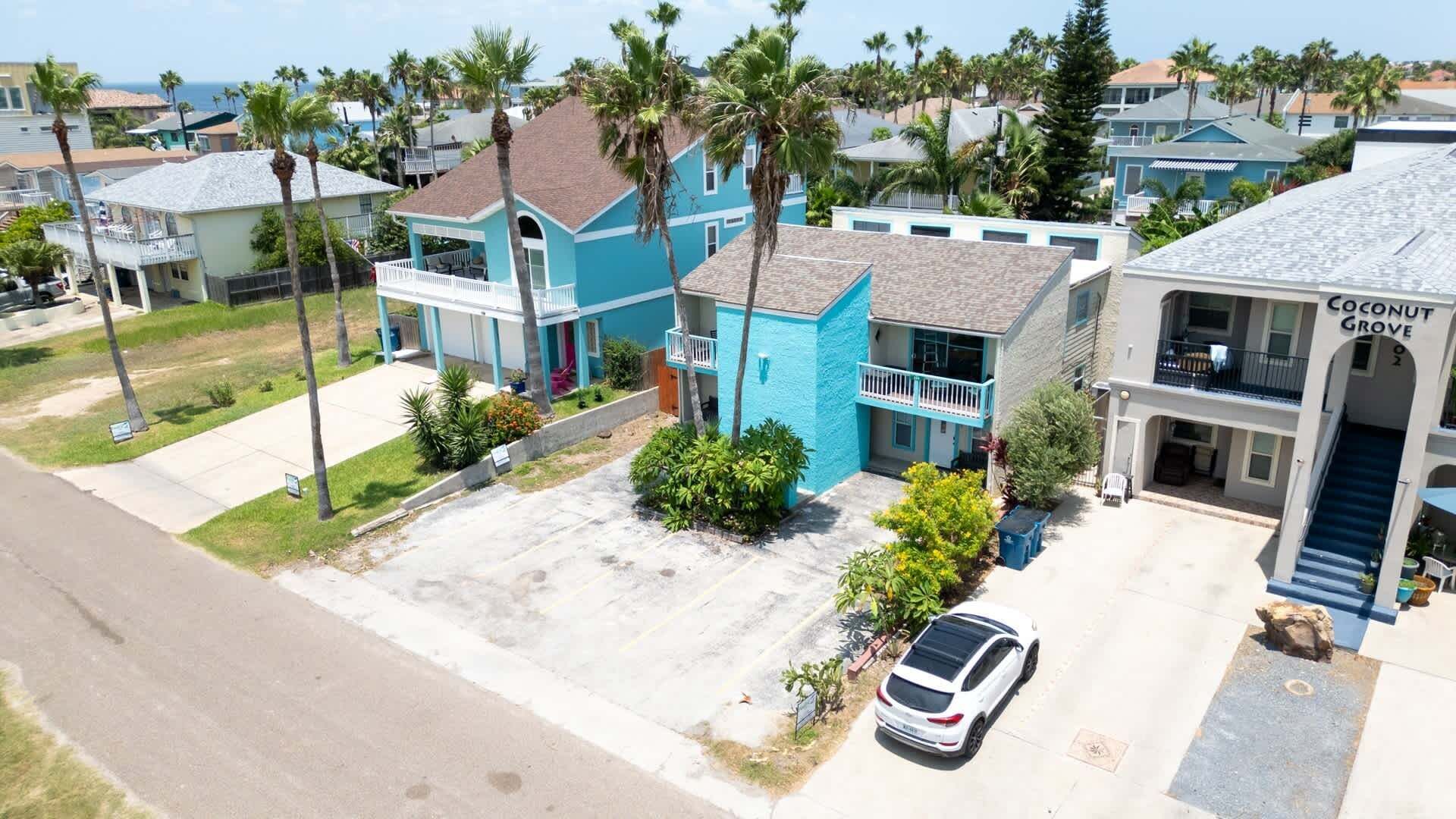 Un quartier résidentiel avec des maisons, une voiture garée et un bâtiment portant l’inscription « Coconut Grove ».
