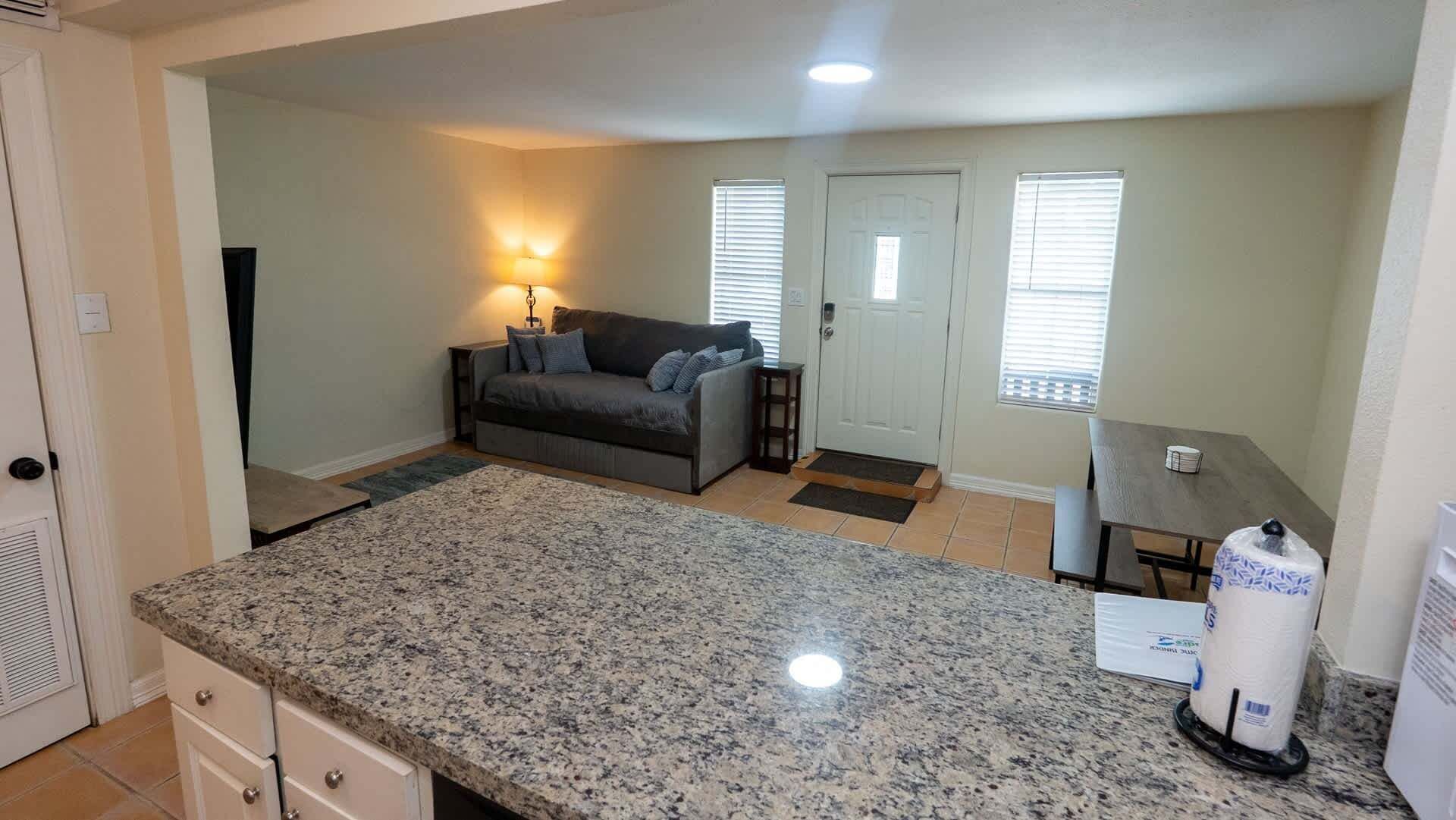 A compact living space with a kitchen area, a sofa, and a dining table.