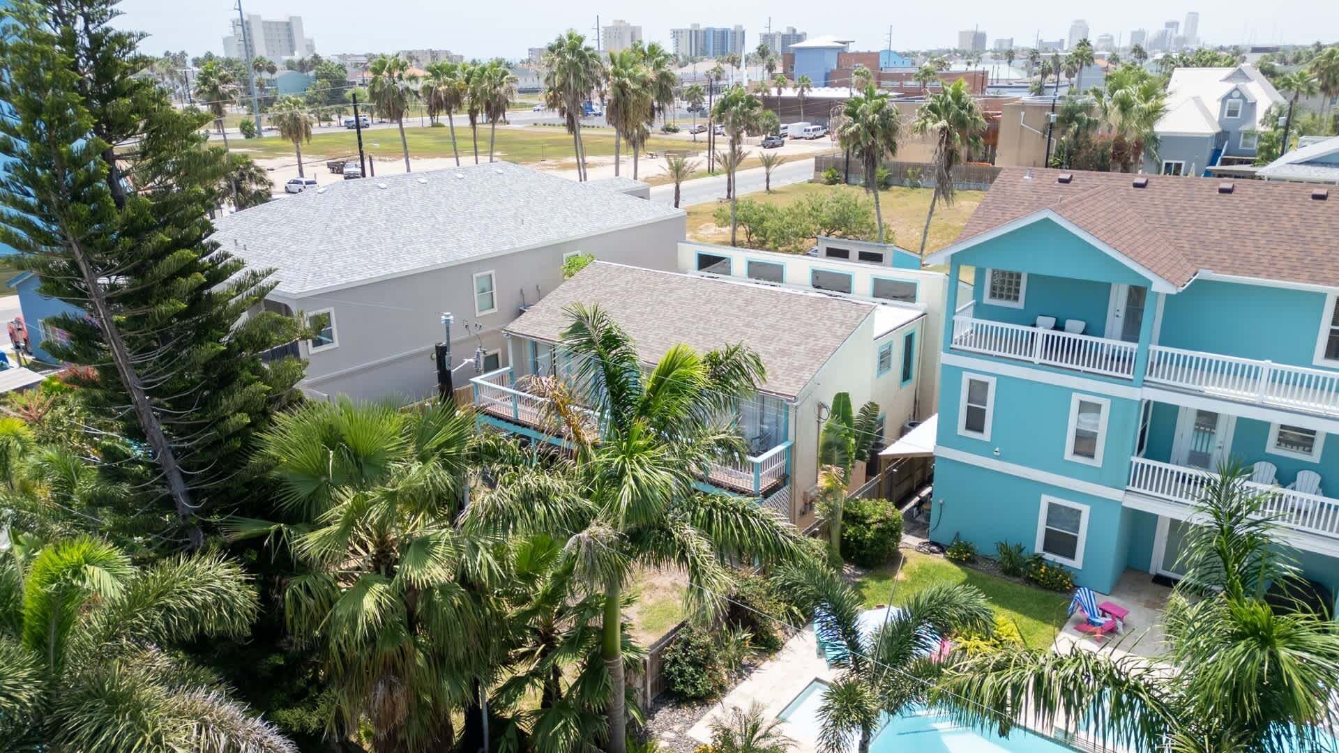 A residential area with a pool, multiple-story buildings, and palm trees.
