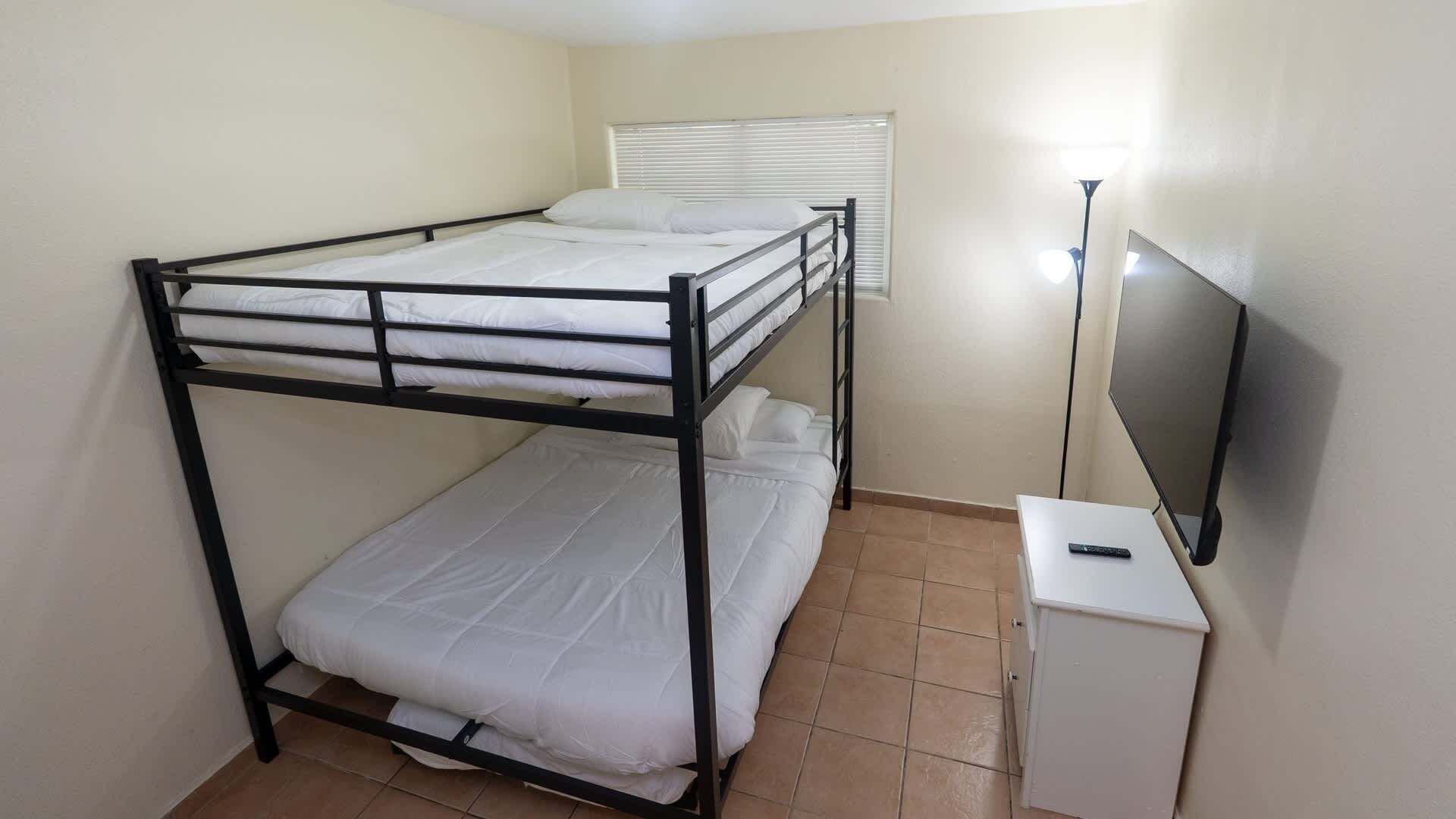A bunk bed room with a television and a cabinet.