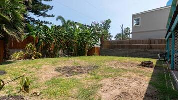 A backyard with a grassy area, a wooden fence, and a building with a blue door.