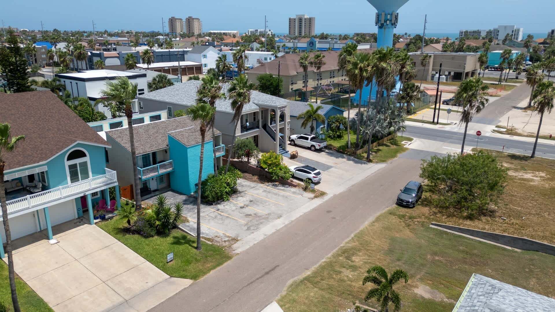 A residential area with a blue building, a parking lot, and a road.