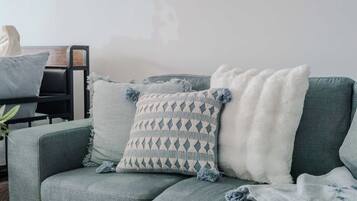 Un salon moderne avec un canapé gris, un coussin décoratif à motifs et un plaid blanc et moelleux.