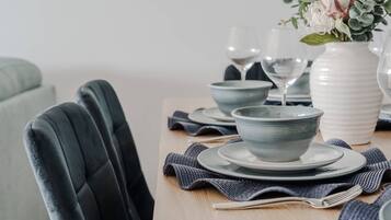 Une table à manger dressée avec des assiettes, des bols et un vase rempli de fleurs.