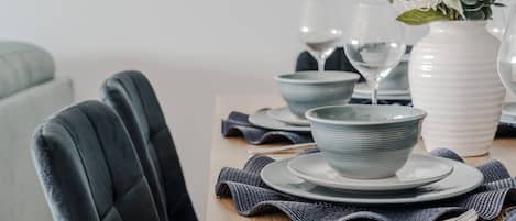 Une table à manger dressée avec des assiettes, des bols et un vase rempli de fleurs.