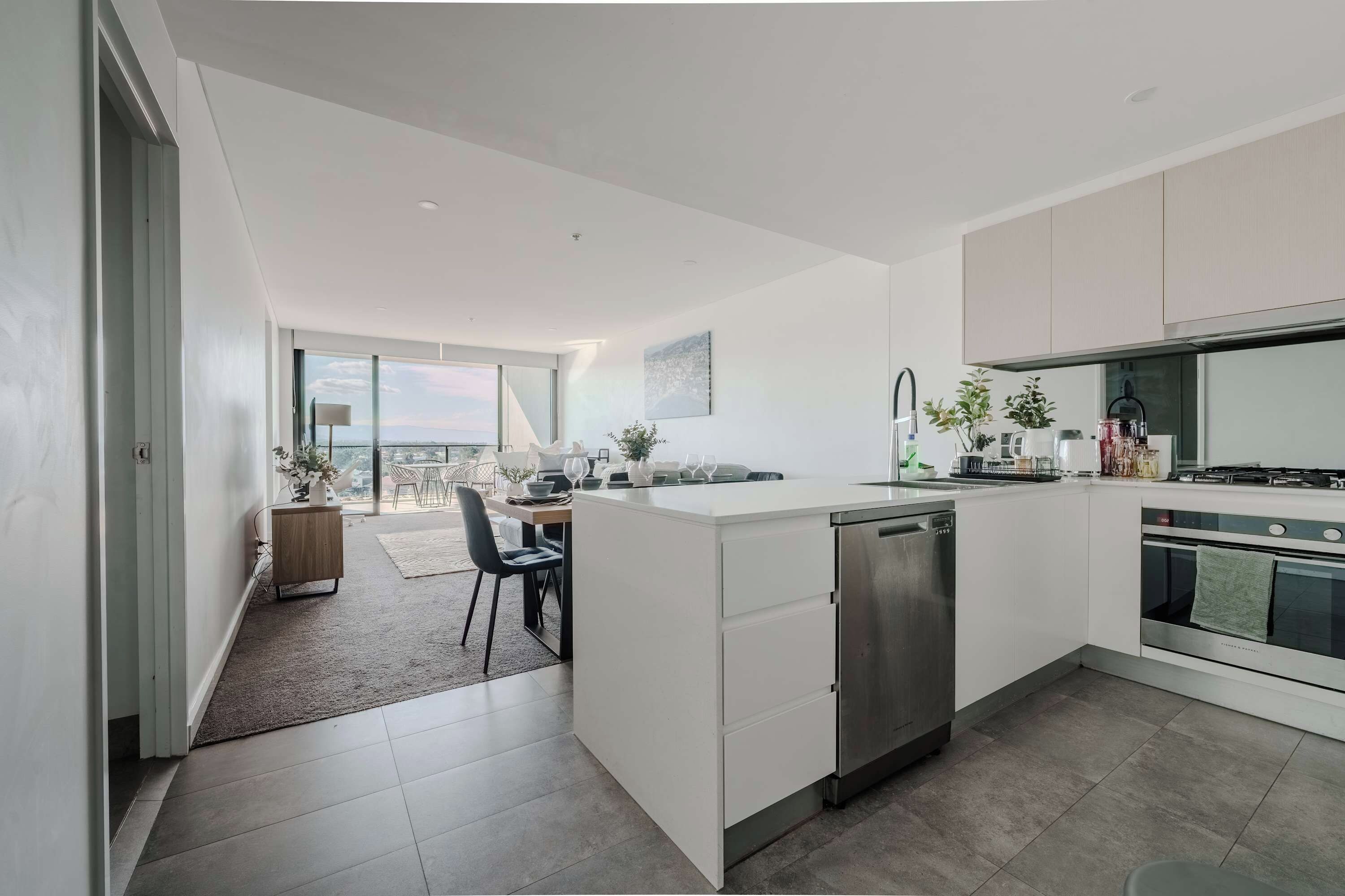 Een moderne keuken met een vaatwasser, fornuis en een eetgedeelte met uitzicht.