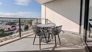 Un balcon avec une table et des chaises, une vue dégagée sur le paysage urbain et une architecture moderne.