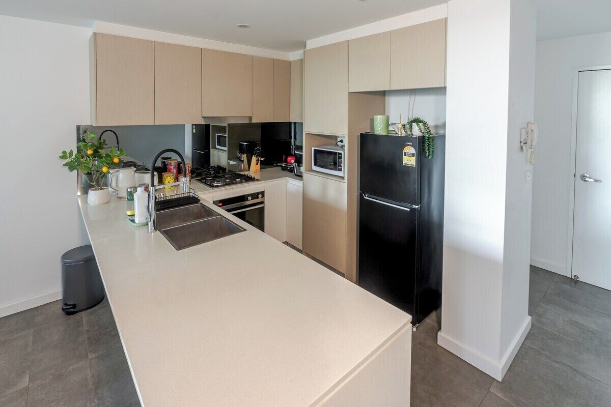 Een moderne keuken met een centraal eiland, roestvrijstalen apparatuur en lichtkleurige kastjes.
