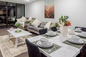 Ein Essbereich mit einem Tisch für vier Personen, einer Couch und einem großen Fenster.