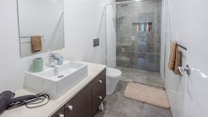 Un bagno moderno con doccia vetrata, lavandino bianco e servizi igienici.