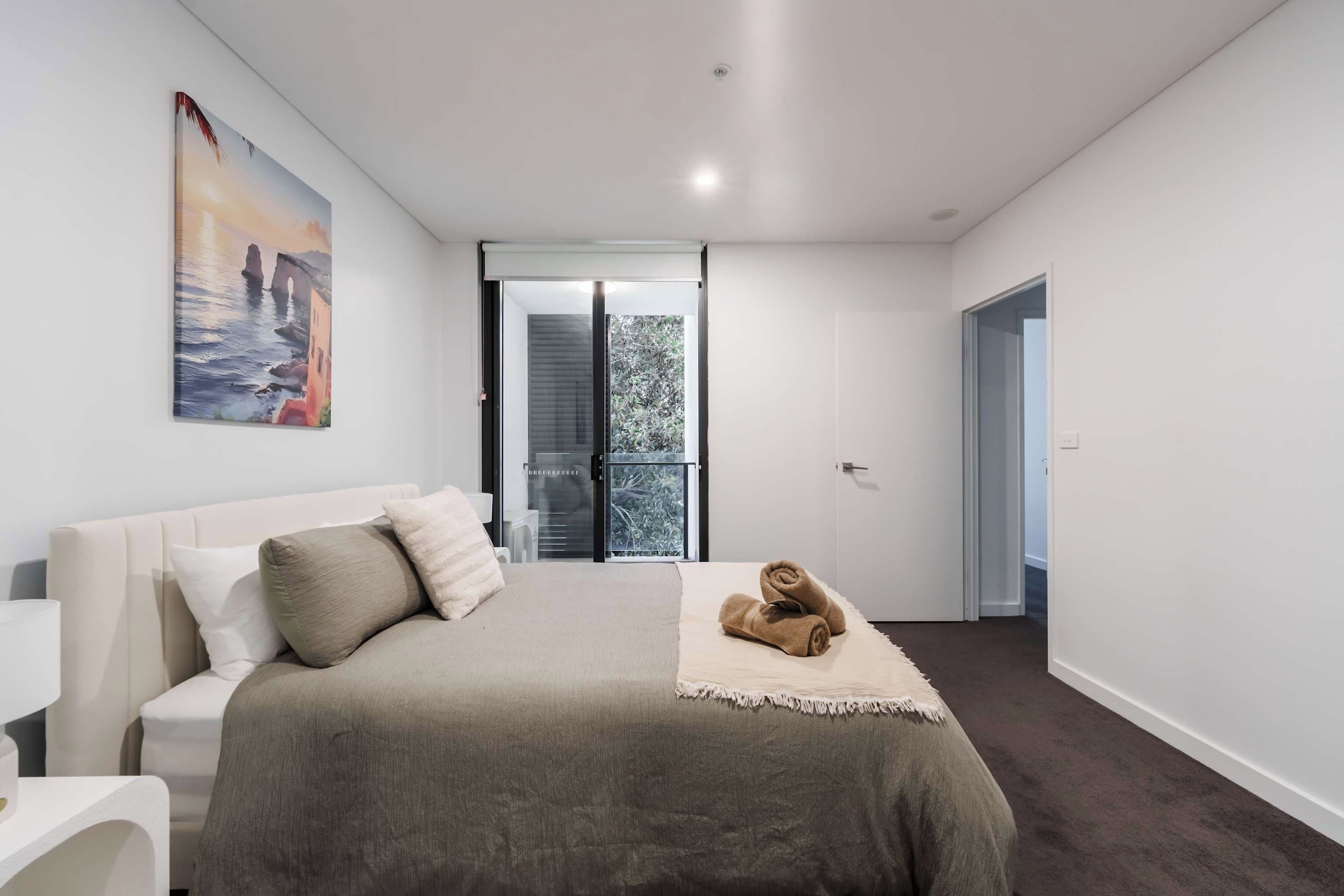 Een slaapkamer met een bed, een schilderij en uitzicht op het landschap.