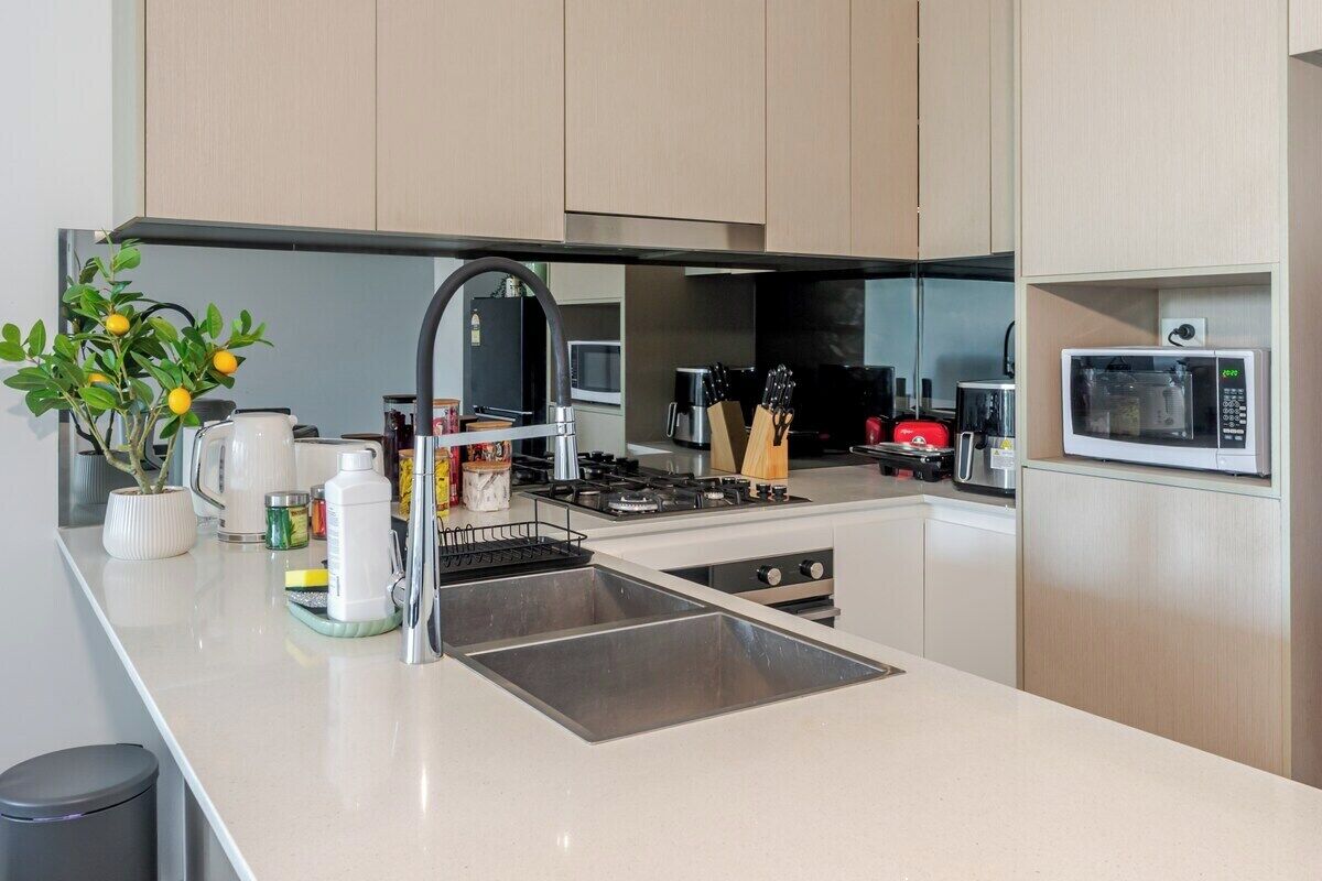 Een moderne keuken met een roestvrijstalen spoelbak, een gasfornuis en een magnetron.