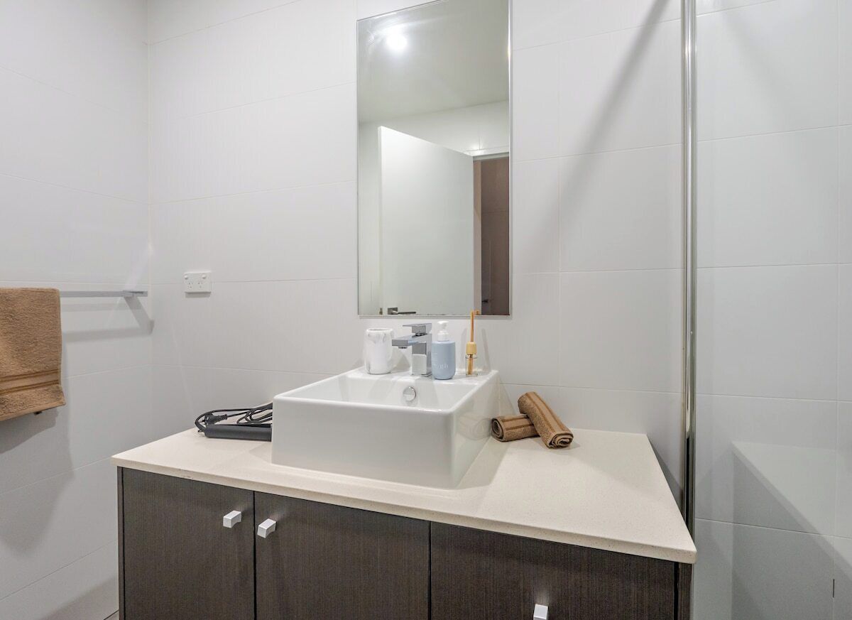 Une salle de bain avec un lavabo blanc, un miroir et une serviette posée sur le comptoir.