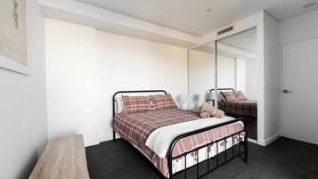 Een slaapkamer met een enkel bed, een nachtkastje, een spiegel en een kledingkast.