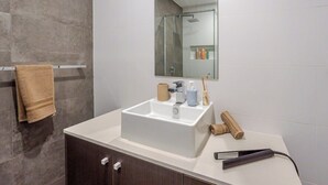 A bathroom with a white sink, dark wooden cabinets, a towel rack, and a mirror. - Filioque | Mountain View | Parking | Central (Wollongong)