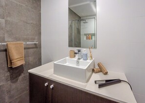 A bathroom with a white sink, dark wooden cabinets, a towel rack, and a mirror. - Filioque | Mountain View | Parking | Central (Wollongong)