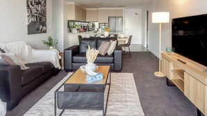 A modern living room with a sofa, coffee table, and TV stand. - Filioque | Mountain View | Parking | Central (Wollongong)