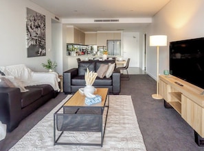 A modern living room with a sofa, coffee table, and TV stand. - Filioque | Mountain View | Parking | Central (Wollongong)