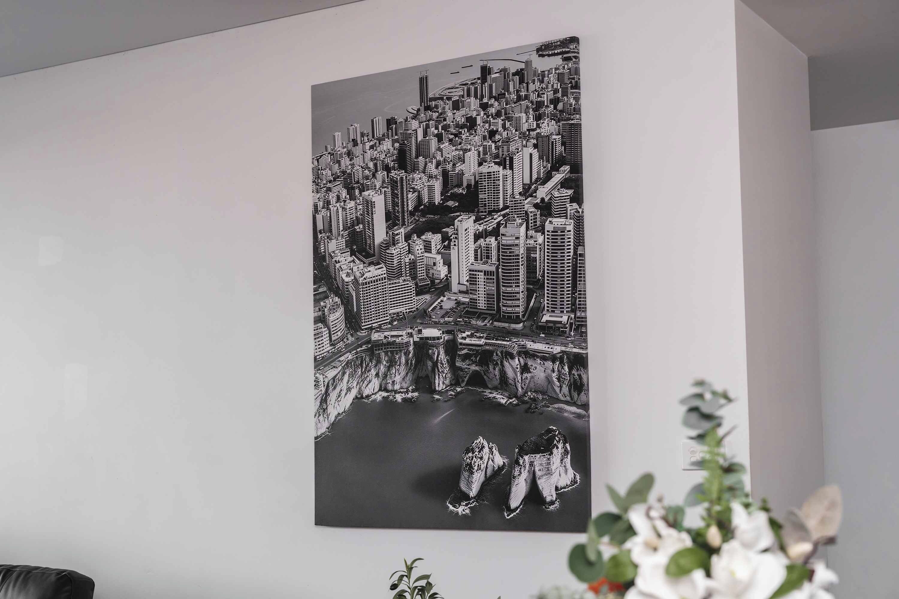 Une œuvre d’art représentant un paysage urbain en noir et blanc, accrochée à un mur.