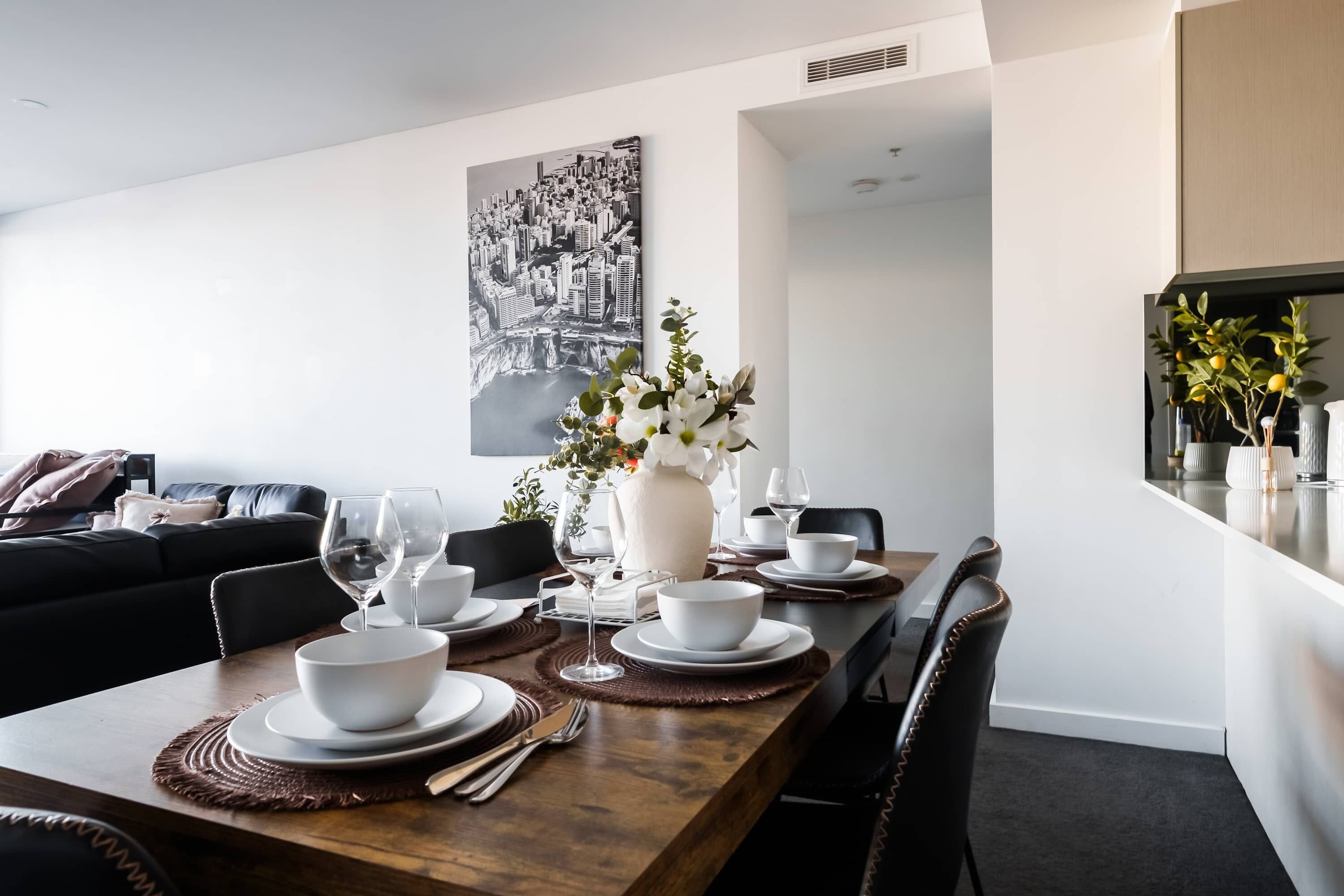 Un espace repas moderne avec une table en bois dressée pour quatre personnes, entourée de chaises noires.