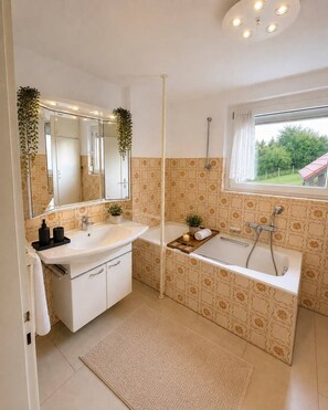 Un baño moderno con lavamanos doble, bañera y un espejo grande.