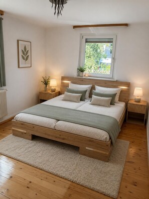 Un dormitorio con una cama de madera, mesitas de noche, un ventanal con vistas y un radiador.