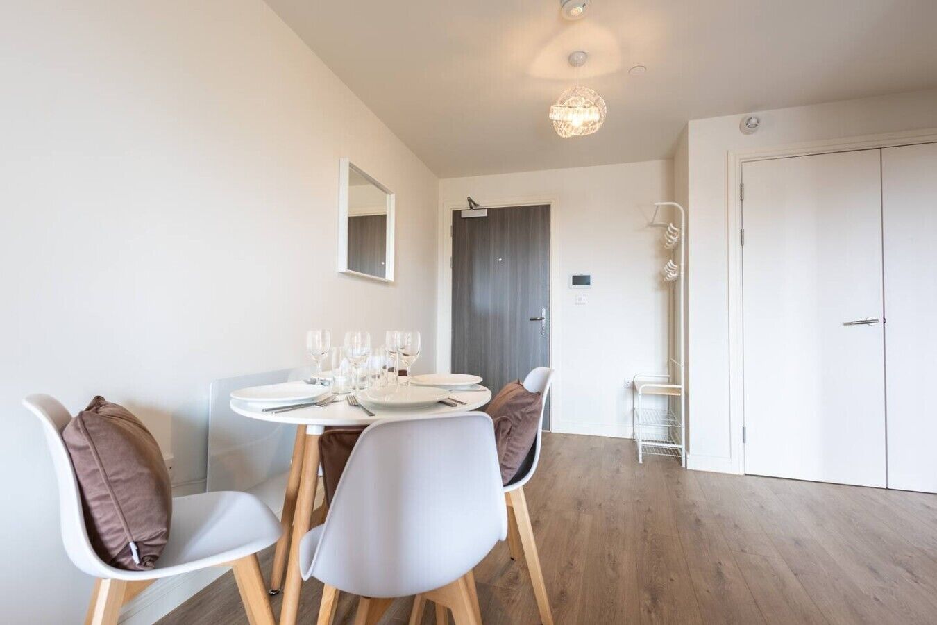 A dining area with a round table set for four, white chairs, and a hanging light fixture.