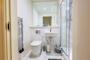 Un bany modern amb vàter, rentapel i plat de dutxa.