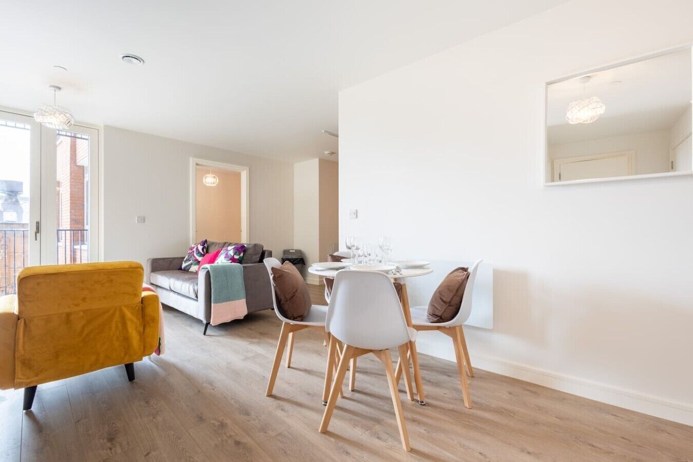 A modern living room with a sofa, a dining table with chairs, and a yellow armchair.