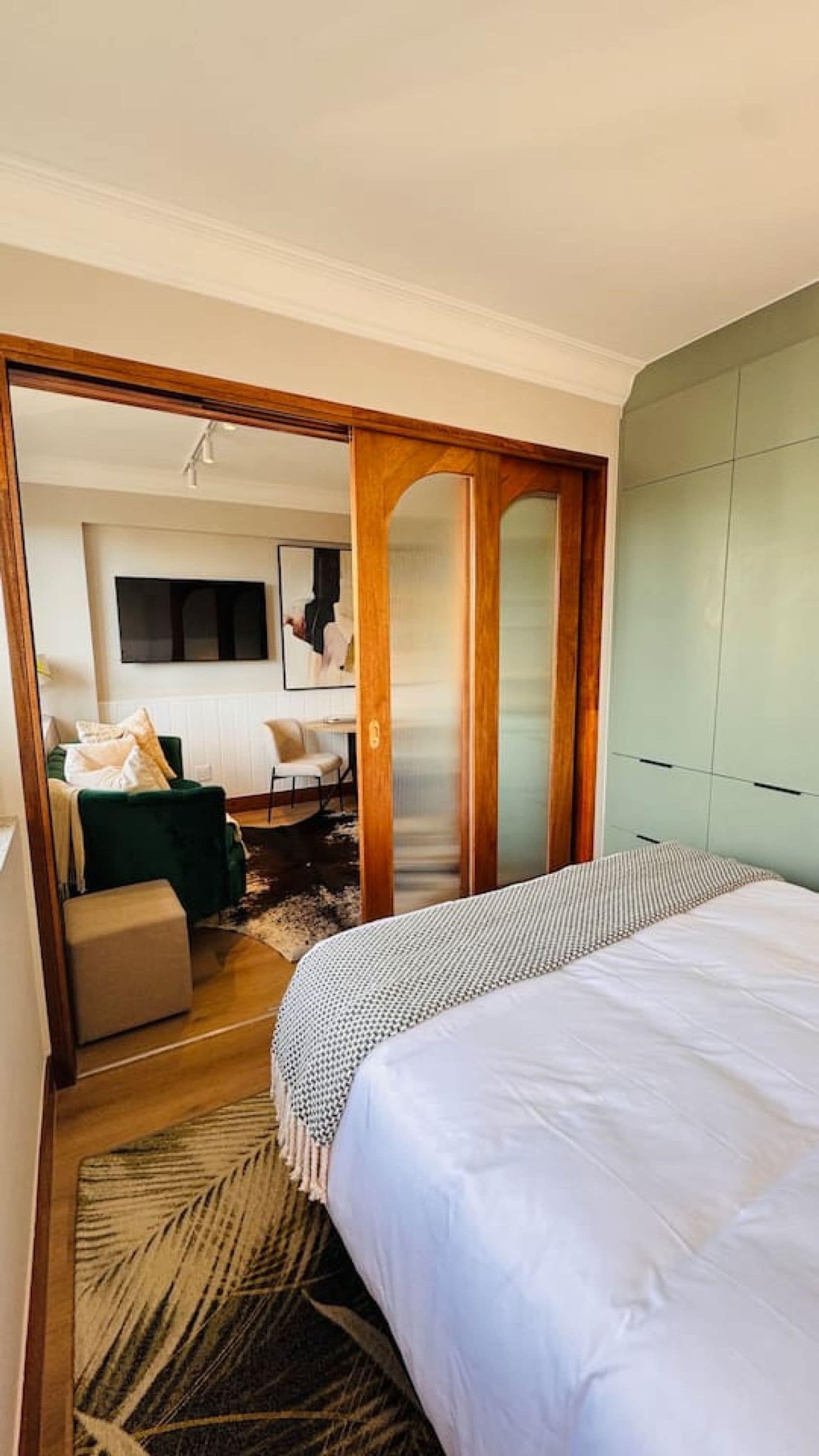 A hotel room with a bed, a sofa, a television, and a wardrobe.