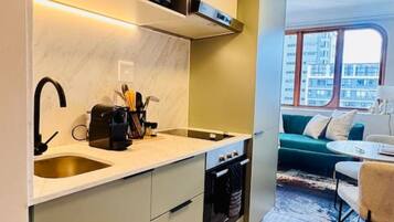 A modern kitchen with a built-in oven, a sink, and a microwave. There is a dining area with a table and chairs.