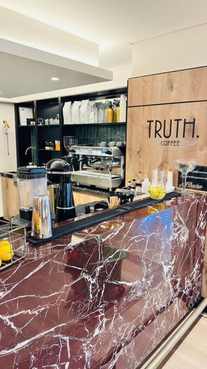 Ein Kaffeehaus mit Marmortheke, Kaffeemaschinen und einem Schild, auf dem 'TRUTH COFFEE' steht.