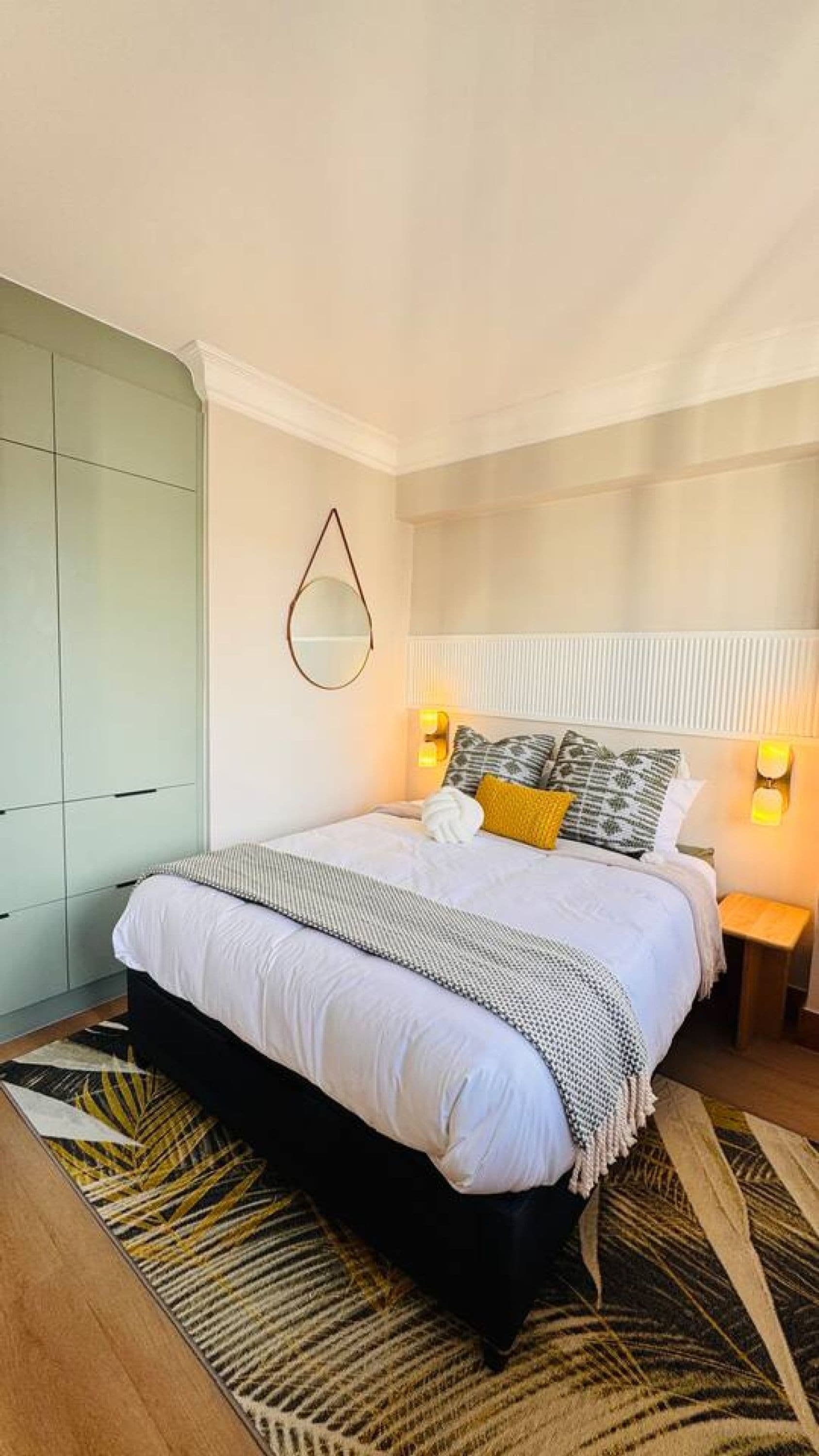 Une chambre à coucher comprenant un lit, des tables de chevet, une armoire et un miroir.