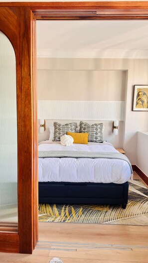 Ein Schlafzimmer mit einem Bett, Nachttischlampen, einem gemusterten Teppich und einem hölzernen Rahmen.