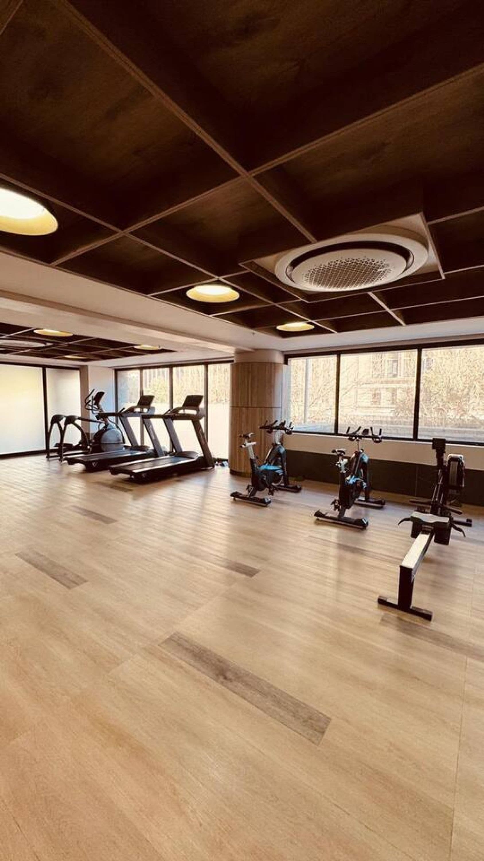 Une salle de sport équipée de matériel d’exercice, dotée de grandes fenêtres et d’un plancher en bois.