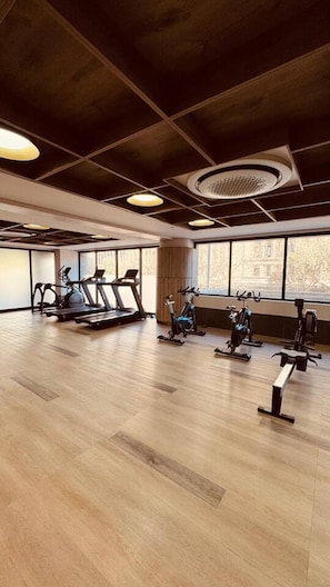 Ein Fitnessstudio mit Trainingsgeräten, großen Fenstern und Holzboden.