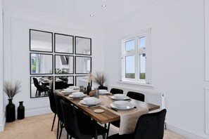 Ein Esszimmer mit einem langen Tisch, gedeckt für sechs Personen, weißen Wänden und einem Fenster mit Blick.