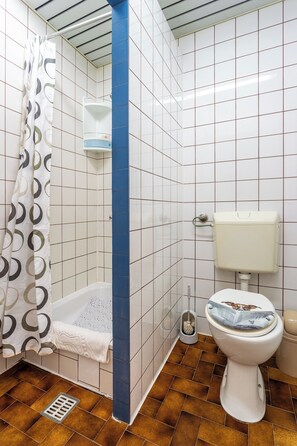 A bathroom with white tiled walls, a blue vertical accent, a shower curtain, a toilet, and a floor drain. - A1 - Cozy apt w Pool & big Terrace, 2 min to Beach (Dugi Rat)