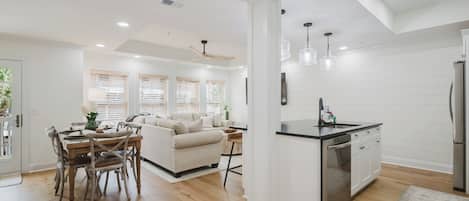 A modern kitchen with a central island, wooden dining table, and chairs.